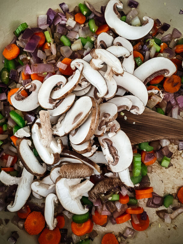 Adding in the mushrooms to the vegetables