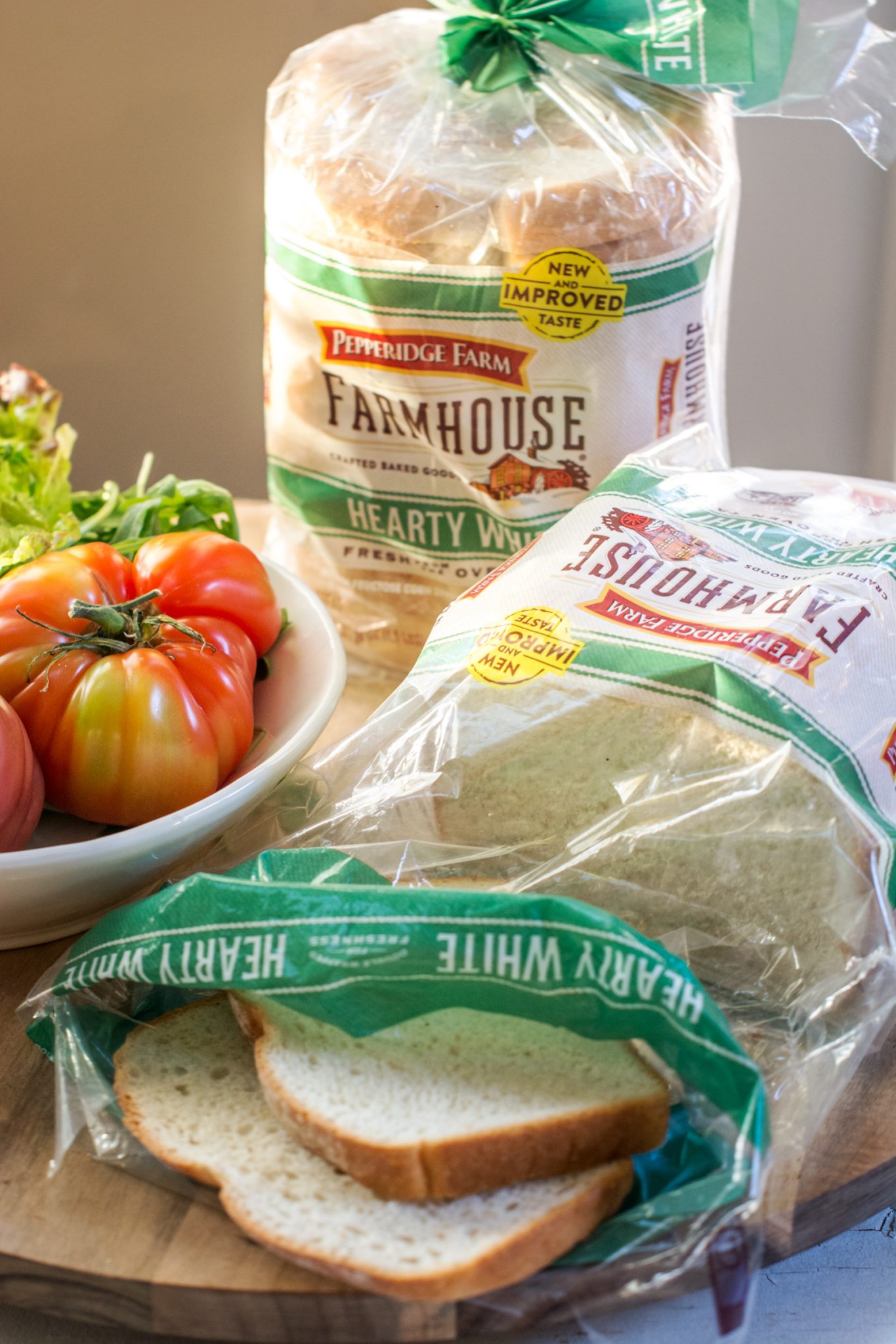 Pepperidge Farm hearty white bread in wrapping beside a bowl of tomatoes.