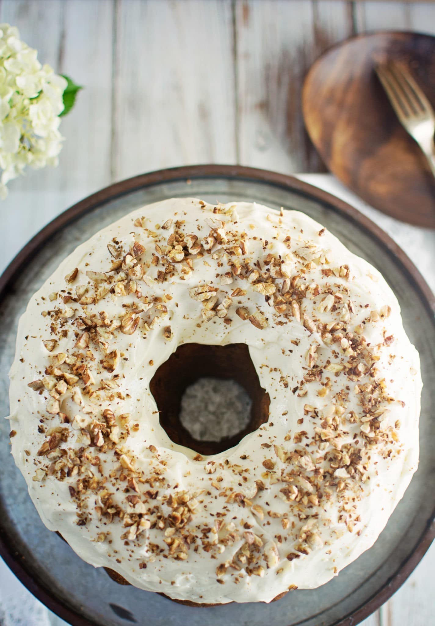 Homemade Hummingbird Bundt Cake on white table garnished with walnuts