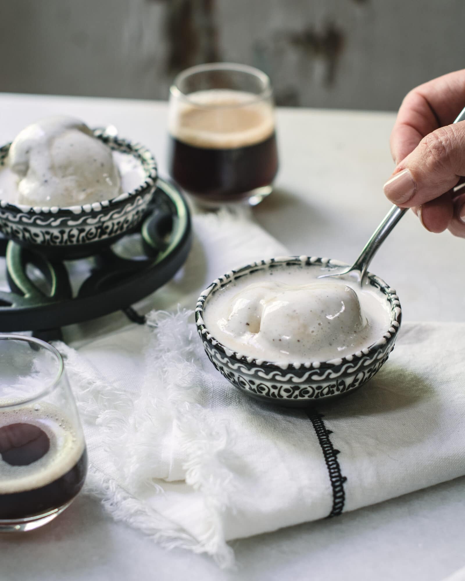 Serving affogato in bowls on white table with hand holding spoon