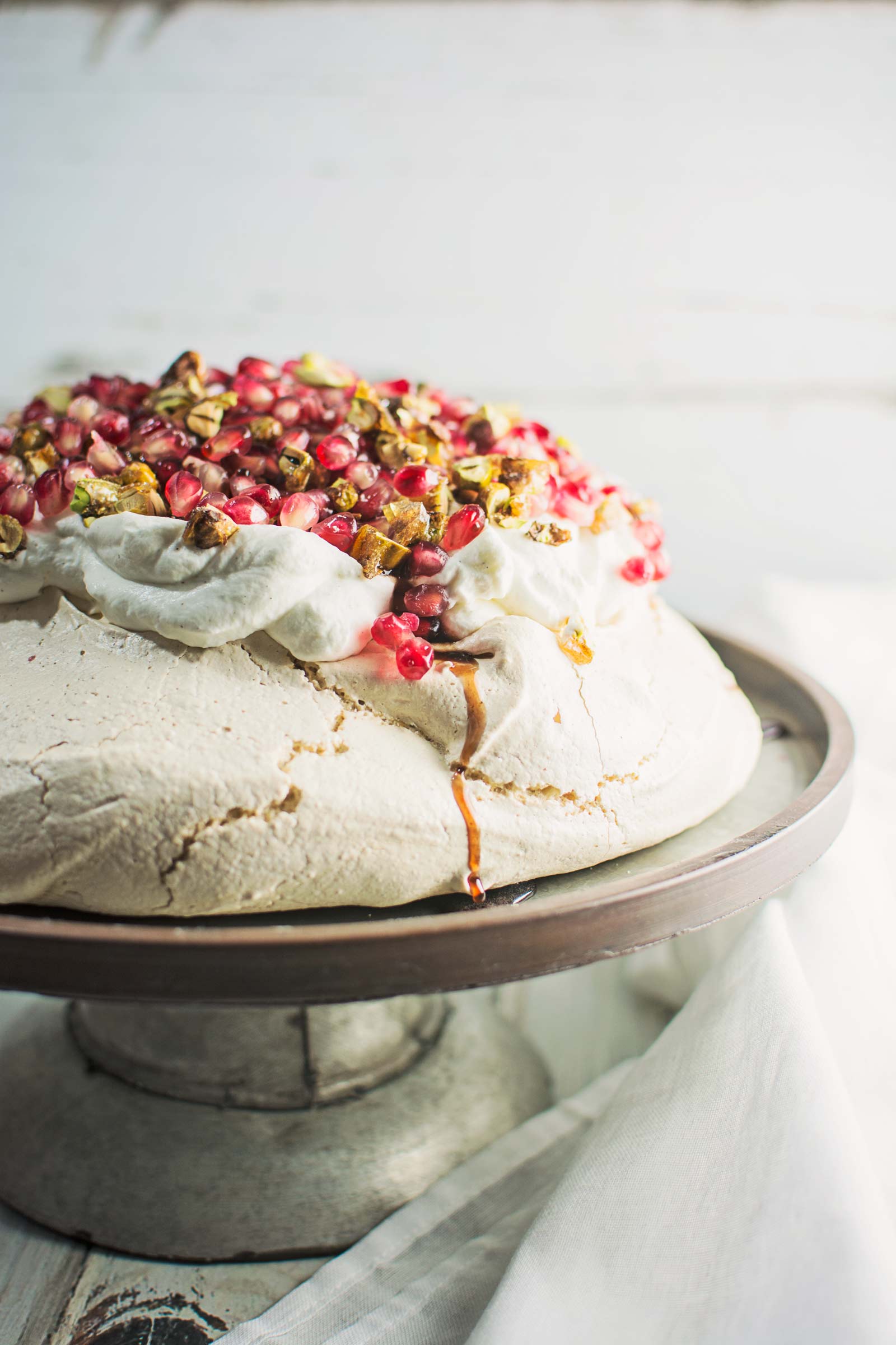 A gorgeous Winter Pavlova, with scattered pomegranate seeds, and topped off with pistachio brittle and plenty of cardamom scented cream! Recipe @LittleFiggyFood