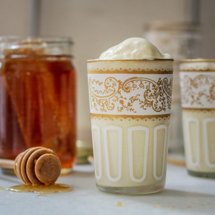 Rosemary infused Honey Ice Cream in decorative glasses beside a jar of honey