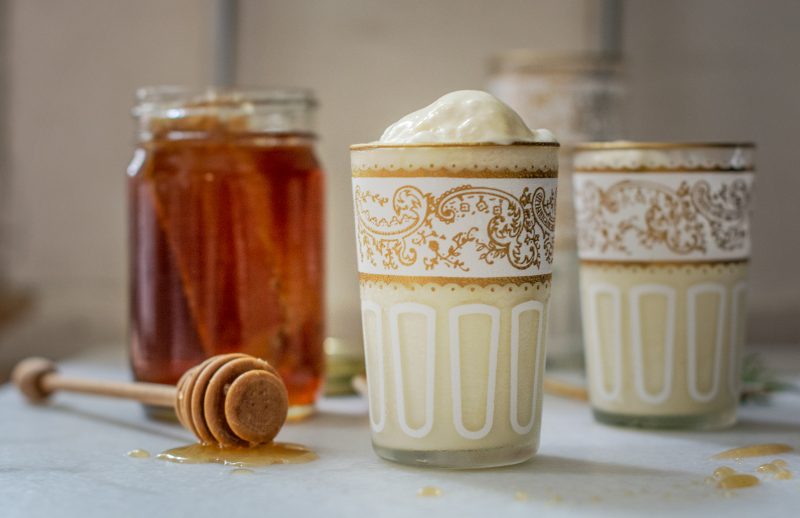 Rosemary infused Honey Ice Cream in decorative glasses beside a jar of honey