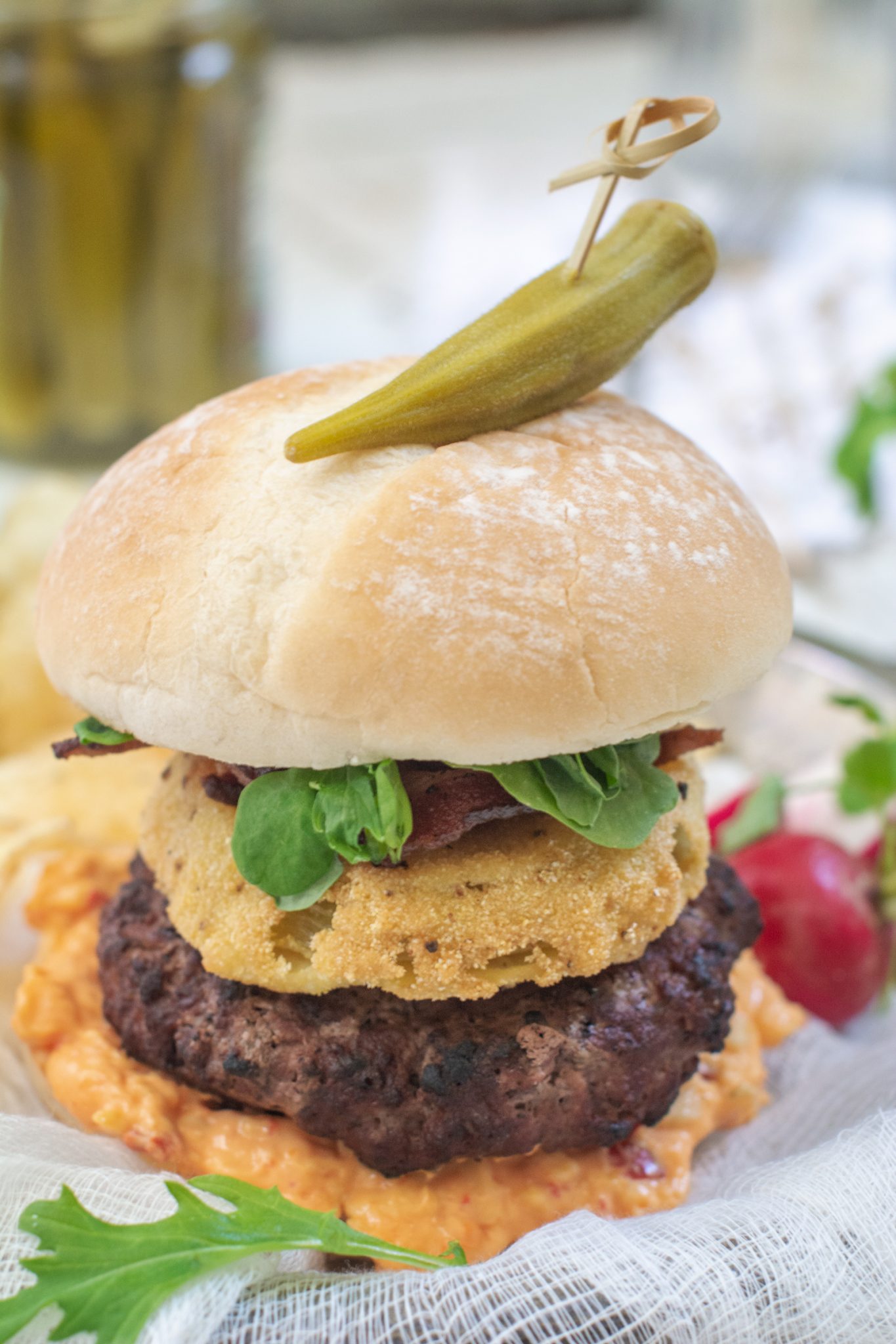 A Southern Burger topped with pimiento cheese, fried green tomatoes, lettuce and bacon.