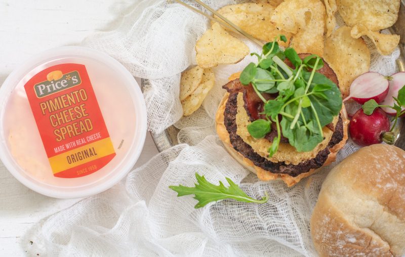 Prices pimiento cheese in packaging beside a hamburger with toppings