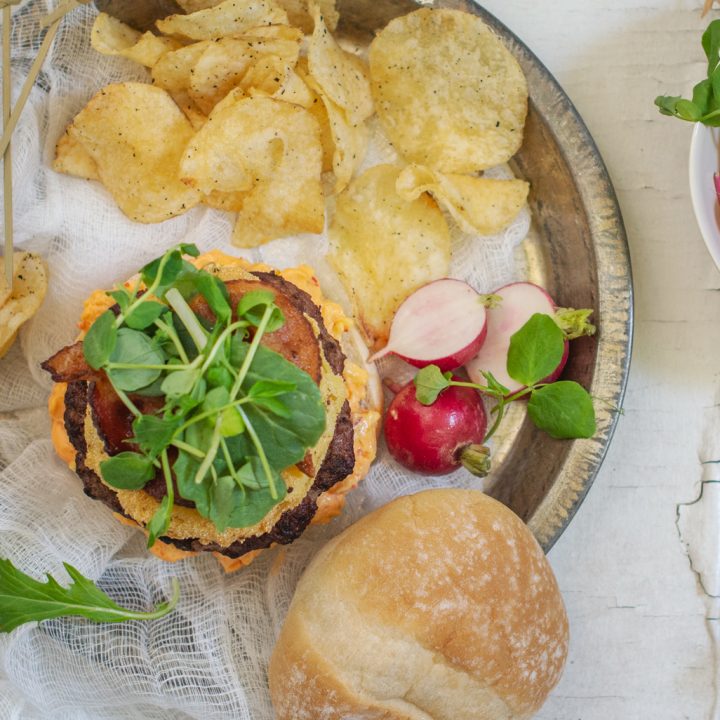 A Southern burger recipe with lettuce on top and a side of potato chips