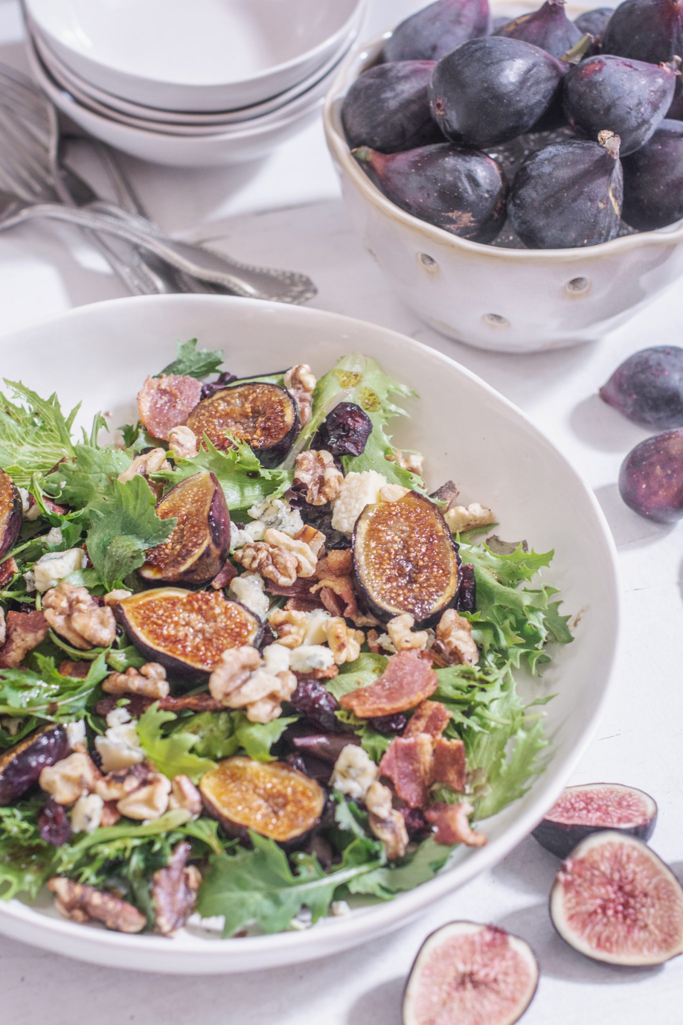 Fresh Grilled Fig Salad in large white bowl with a bowl of figs to the side.