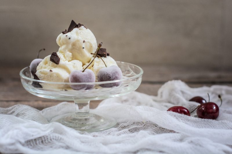 Scoops of homemade vanilla ice cream served with chocolate pieces and cherries