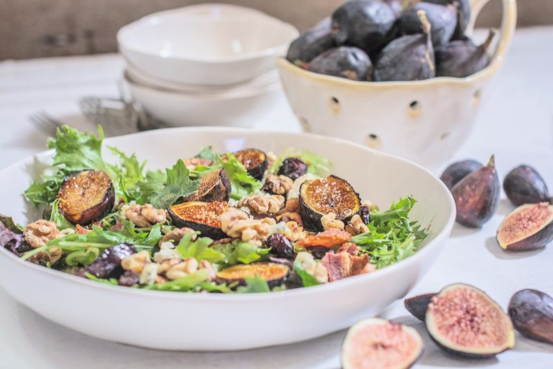 Ready to serve grilled fig salad in large white bowl.