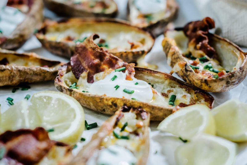 Game day recipe for loaded potato skins filled with bacon, chives, cheese and sour cream.