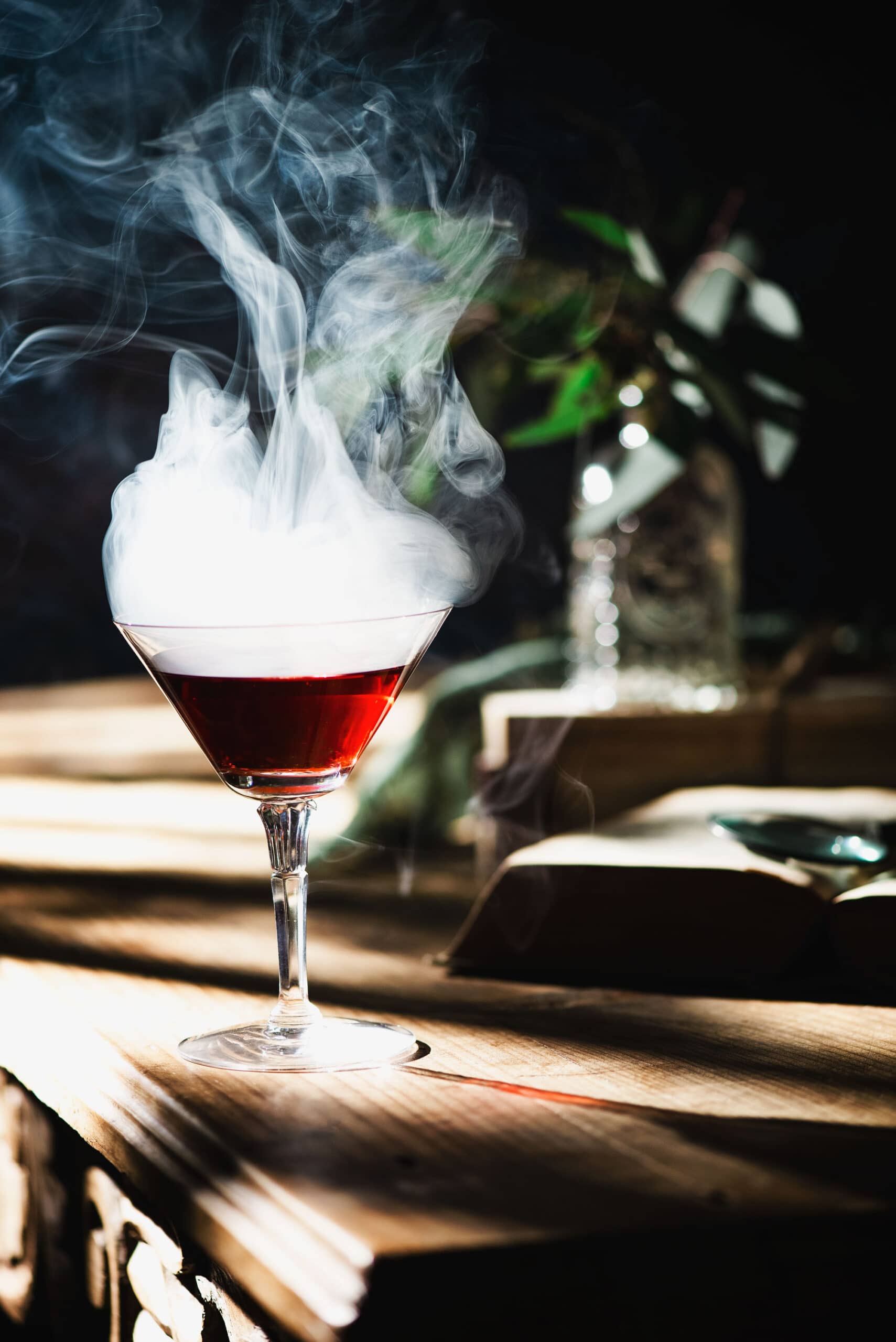 Martini glass with Washington apple cocktail and smoke on wooden table